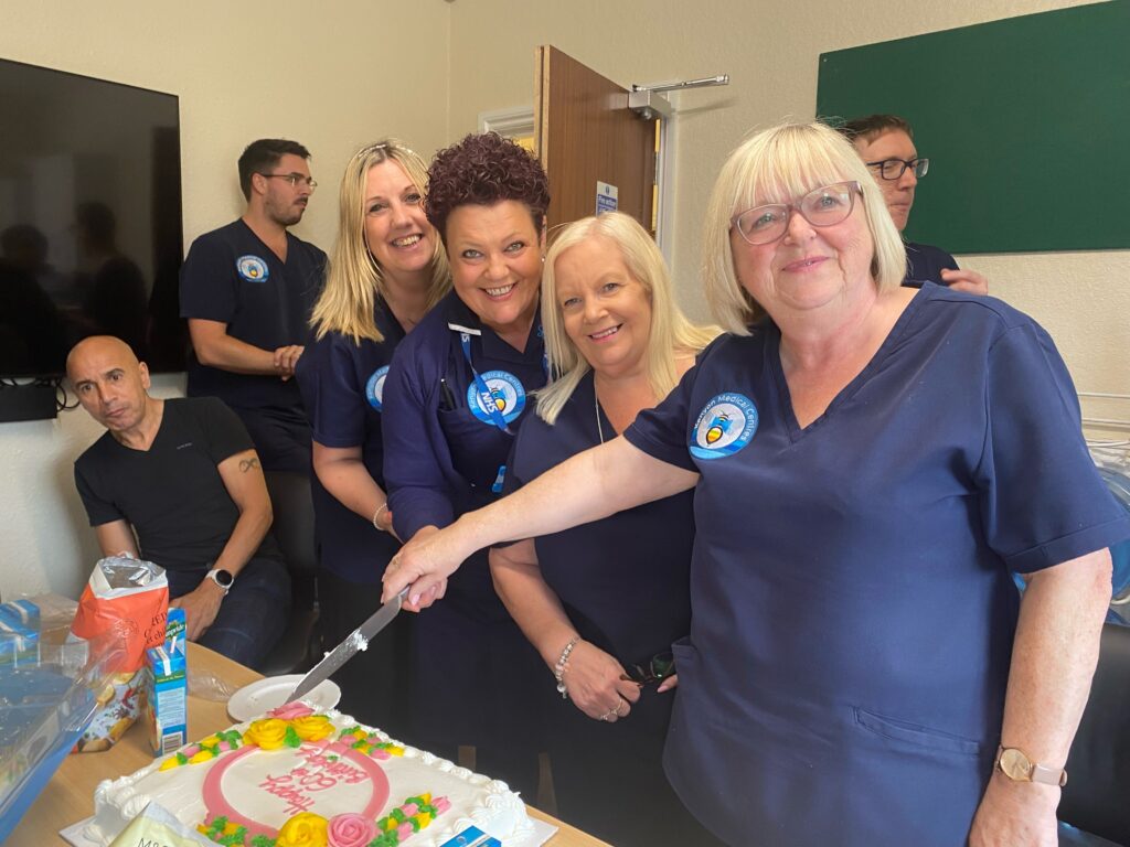 4 ladies in a group photograph cutting a birthday cake